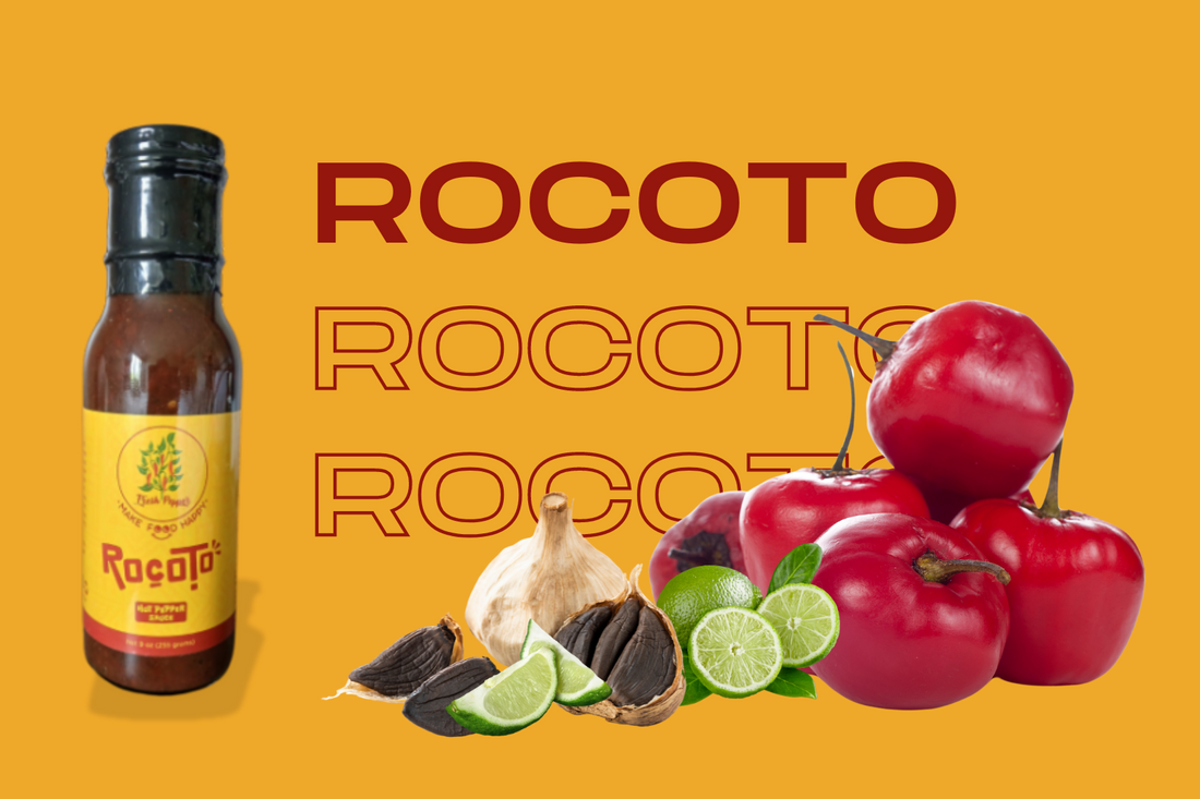 bottle of rocoto hot pepper sauce next to rocoto peppers, lime, and black garlic